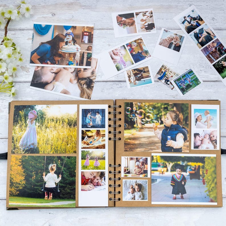 May include: An open scrapbook with various photographs, including family portraits, children playing, and special events. The scrapbook is spiral-bound with a kraft paper cover, and several loose photos are scattered around it.