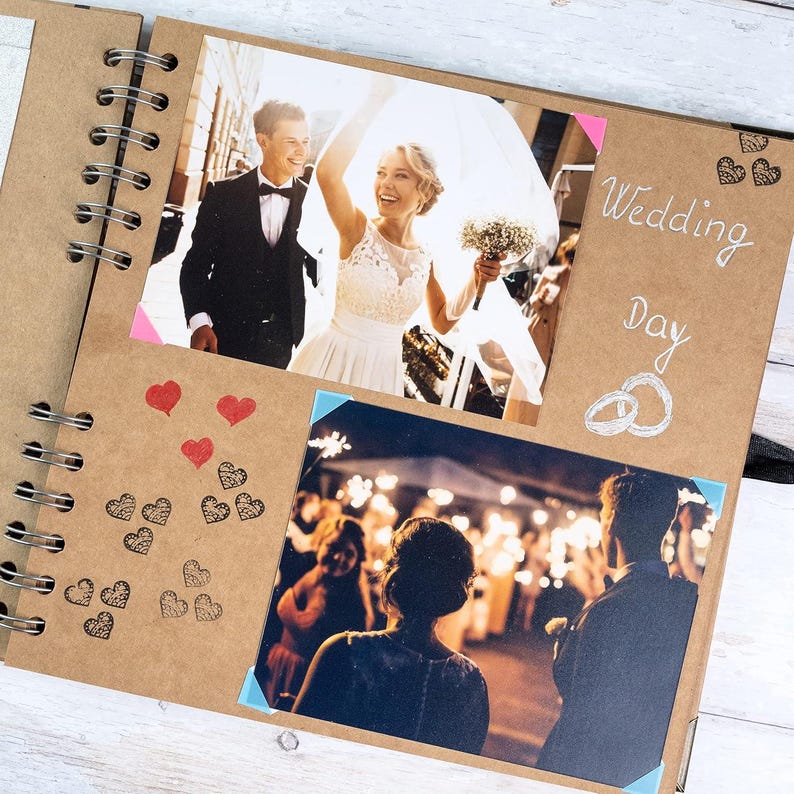 May include: A spiral-bound scrapbook with a kraft paper cover, featuring wedding photos. The album includes photos of a bride and groom, and a reception. Decorative elements include hearts and the words "Wedding Day".