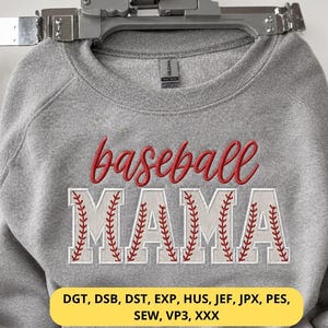 Può includere: Una felpa grigia con le parole "baseball MAMA" ricamate in rosso e bianco. La parola "baseball" è in un carattere corsivo e "MAMA" è in un carattere a tema baseball. La felpa è appesa a una gruccia di metallo.