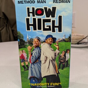 May include: A VHS tape for the film "How High" starring Method Man and Redman. The cover features a blue sky background with the title in large black letters and a red circle. The actors are shown on a grassy field.