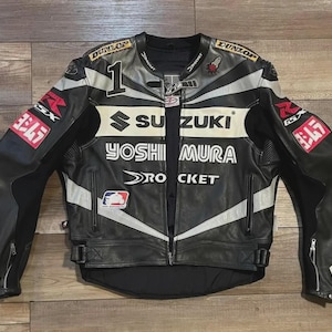 May include: Black and white leather motorcycle jacket with Suzuki and Yoshimura logos. The jacket features a number 1 on the upper left chest, white stripes, and red and white patches. The jacket has a zipper closure and multiple pockets.