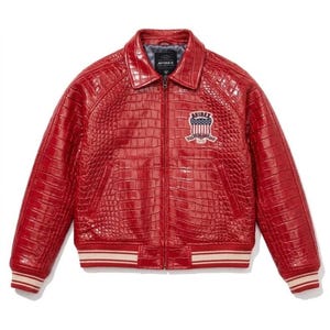 May include: A red leather jacket with a crocodile texture. The jacket features a collared neckline, a zip closure, and a chest patch with the text "AVIREX". The cuffs and hem have a striped design.