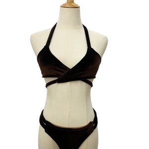 May include: A brown velvet bikini set on a mannequin. The halter-neck top has a wrap-around design, and the bottoms are low-rise with side straps. The fabric has a soft, luxurious appearance, ideal for swimwear.