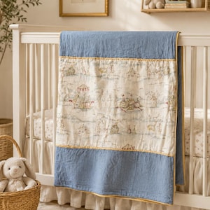 May include: A rectangular baby quilt featuring a central cream-colored panel with a repeating illustration of rabbits in a park setting, bordered by solid dusty blue fabric on the top and bottom, finished with thin yellow piping along the edges.
