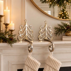 May include: Two silver-toned metal stocking holders shaped like stylized Christmas trees with swirling branches and a star topper. Each holder features a curved hook at the base to support a hanging stocking, finished with a polished metallic sheen.