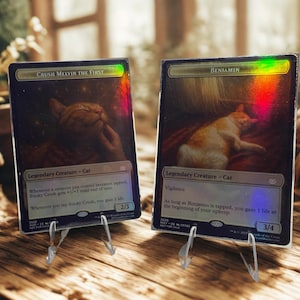 May include: Two collectible trading cards with cat illustrations. One card is titled "Crush Melvin the First" and the other is "Benjamin." Both cards have a holographic sheen and are displayed on clear stands, showcasing the cat-themed artwork.