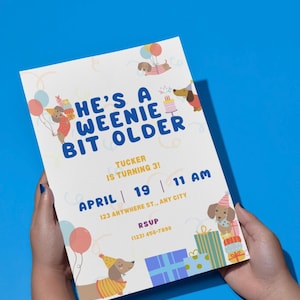 May include: A rectangular birthday invitation card featuring cartoon dachshunds wearing party hats, colourful balloons, and gift boxes. The text reads: HE'S A WEENIE BIT OLDER, TUCKER IS TURNING 3!, APRIL 19, 11 AM, 123 ANYWHERE ST., ANY CITY, RSVP (123) 456-7890.