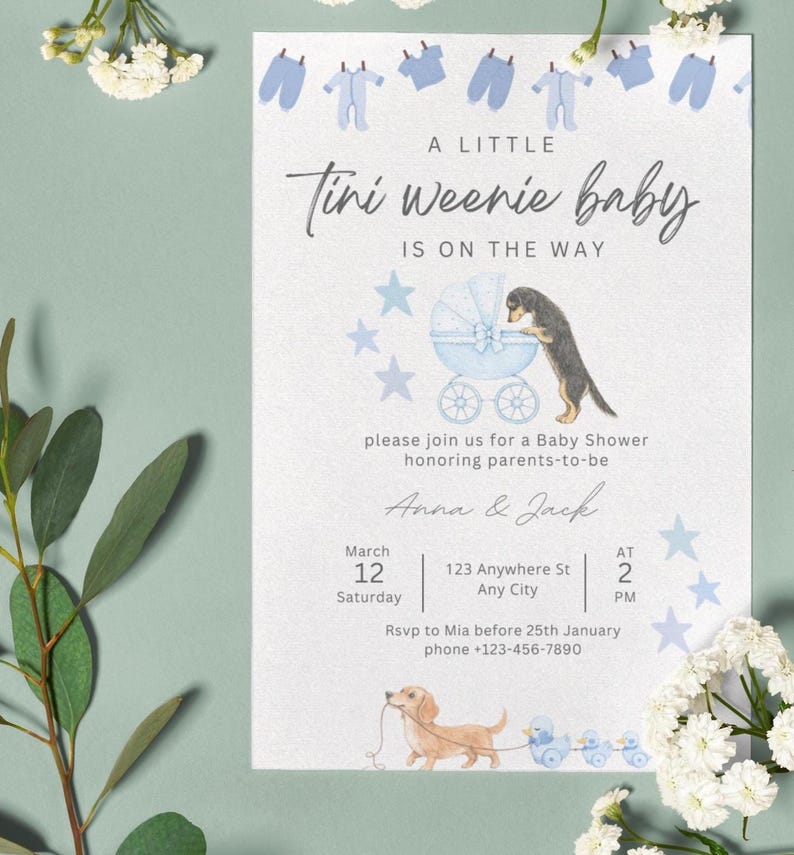 May include: A white baby shower invitation card featuring blue baby clothes, a blue carriage with a dachshund, and a light brown dachshund pulling blue toy ducks. Text reads: A LITTLE Tini weenie baby IS ON THE WAY, Anna & Jack, March 12.