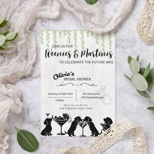 Op de afbeelding: Een uitnodiging voor een bruidsdouche met de tekst "Weenies & Martinis" en "Olivia's Bridal Shower". De uitnodiging heeft een groen wijnstokontwerp en zwarte silhouetten van teckels met martiniglazen.