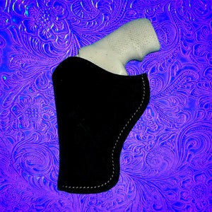 May include: A black leather holster with a white gun inside. The holster is on a purple and blue patterned background.