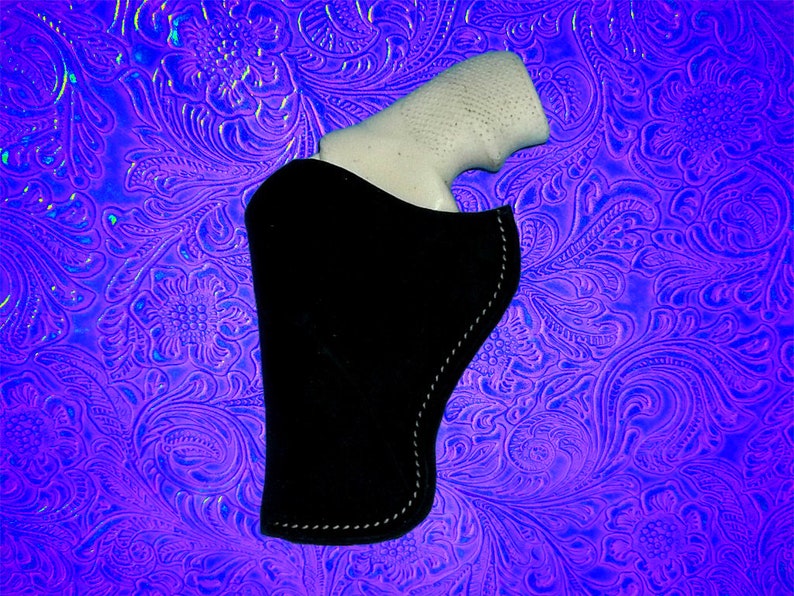 May include: A black leather holster with a white gun inside. The holster is on a purple and blue patterned background.