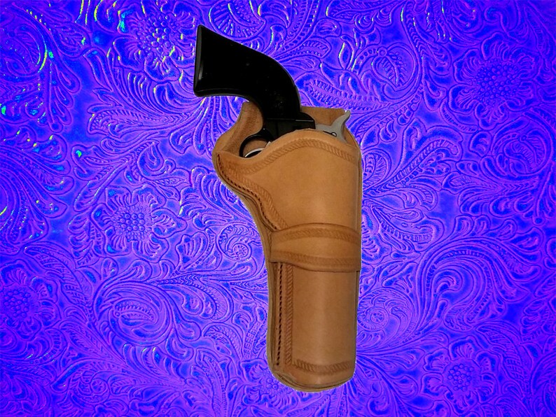 May include: A brown leather holster for a handgun. The holster has a stitched design and is shown against a purple background with a floral pattern.