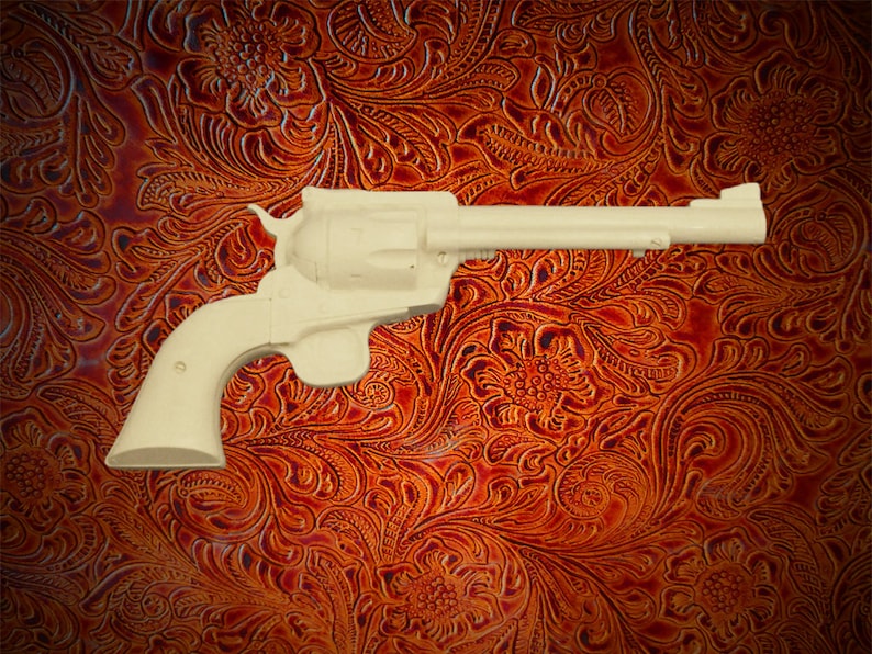 May include: A white plastic toy revolver on a brown patterned background.
