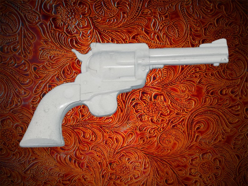 May include: A white plastic toy gun with a black barrel and a brown leather background.