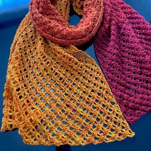 Peut inclure: Une écharpe en crochet avec un dégradé de couleurs orange, jaune et rouge. L'écharpe est réalisée avec un point ajouré délicat.