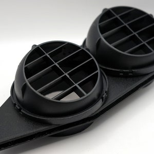 May include: Black plastic vent with two round, circular grilles. The vent is designed to be mounted on a wall or ceiling.