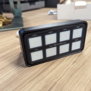 May include: A black rectangular switch panel with eight white buttons and the text "SWITCH-PRO" printed on the front.