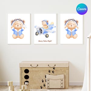 May include: Three framed watercolor prints featuring a teddy bear pilot. The bear wears a blue aviator jacket and goggles. One print shows the bear holding a paper airplane, another in a blue airplane, and the third with hands up. The text "Henry Takes Flight" is on one print.