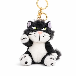 Peut inclure: Un porte-clés en forme de chat en peluche noir et blanc avec un anneau doré. Le chat a les yeux verts, un nez rose et est assis avec une patte levée. Le porte-clés est un accessoire mignon.