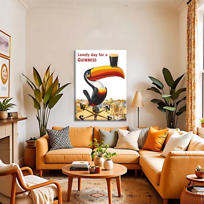May include: A framed print featuring a toucan holding a pint of Guinness. The toucan has a large orange and yellow beak, with the text "Lovely day for a Guinness" above it. The artwork is displayed in a living room with an orange sofa.