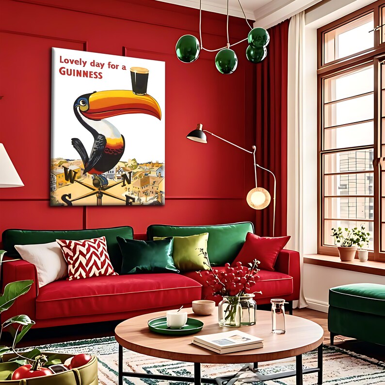 May include: A framed print featuring a toucan with a large orange and yellow beak, holding a pint of Guinness. The text "Lovely day for a Guinness" is above the toucan. The artwork is set against a red wall.