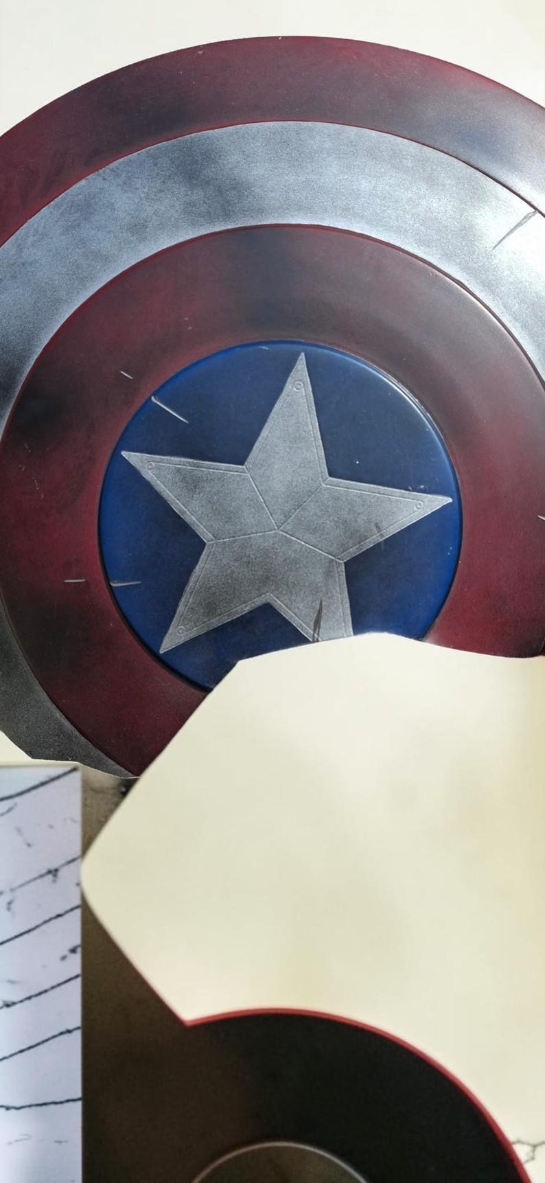 May include: A Captain America shield prop, featuring a blue central disc with a silver star, surrounded by concentric rings of silver, white, and red. The shield is a classic superhero accessory.