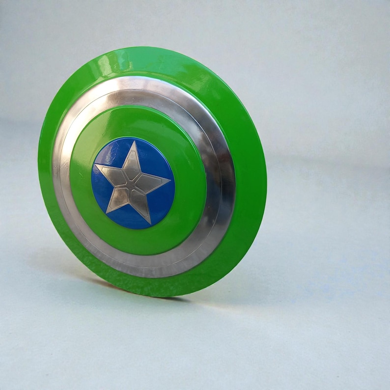 Pu&ograve; includere: Uno scudo verde e argento con un cerchio centrale blu e una stella argentata. Lo scudo ha una finitura lucida e un design circolare, che ricorda l'emblema di un supereroe.