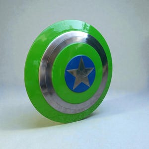 Pu&ograve; includere: Uno scudo rotondo con un anello esterno verde, bande argentate e un centro blu. Una stella argentata &egrave; al centro del cerchio blu. Lo scudo ha una finitura lucida ed &egrave; probabilmente un accessorio di costume.