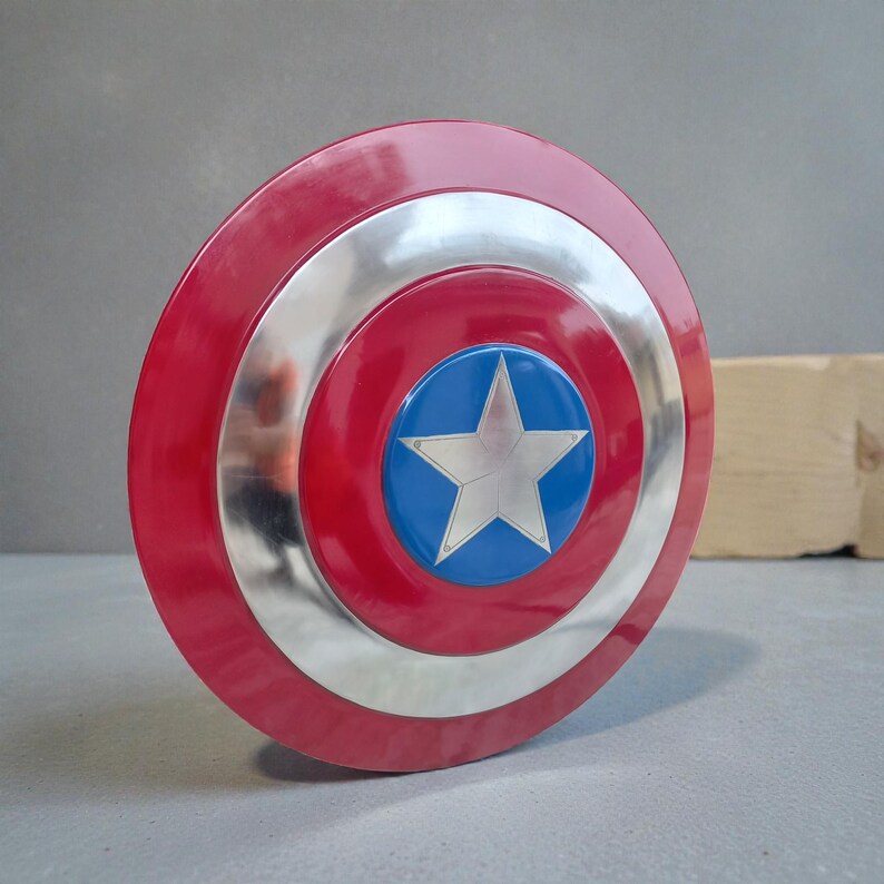 Puede incluir: Un escudo rojo, plateado y azul con un emblema de estrella. El escudo tiene un dise&ntilde;o circular con un anillo exterior rojo, un anillo central plateado y un centro azul con una estrella blanca.
