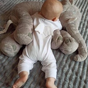 Puede incluir: Una taza de cerámica blanca con asa negra y el texto "But First, Coffee" en negrita negra. La taza se encuentra sobre un fondo borroso, sugiriendo un ambiente acogedor.