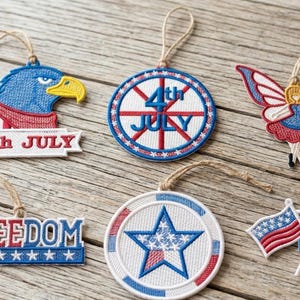 May include: Embroidered patriotic ornaments in red, white, and blue. Designs include an eagle, a butterfly, flags, a star, and the words "4th JULY" and "FREEDOM". Each ornament has a loop for hanging.