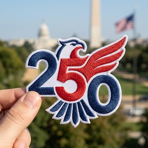 May include: An embroidered patch featuring a stylized eagle design with the number 250. The eagle head and wings are rendered in red and white, while the number 250 and the eagle tail feathers are in dark blue, all outlined in white thread.