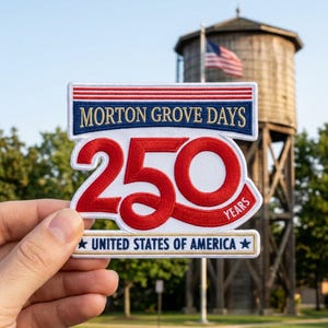 May include: A commemorative patch with the text "MORTON GROVE DAYS 250 YEARS UNITED STATES OF AMERICA." The patch features a red "250" design with a white border and blue and red accents. An American flag and water tower are in the background.