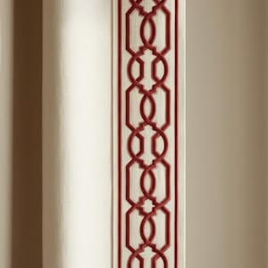 May include: Off-white fabric featuring a vertical border with a repeating geometric design in a rich red colour. The pattern consists of interlocking shapes, providing a decorative element. The fabric is likely a curtain or upholstery material.