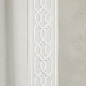 Pode incluir: Painel de cortina branco com uma borda bordada geométrica. A borda apresenta um padrão repetitivo de formas interligadas. A cortina tem uma aparência texturizada e é feita de um tecido de cor clara, adequado para decoração de casa.