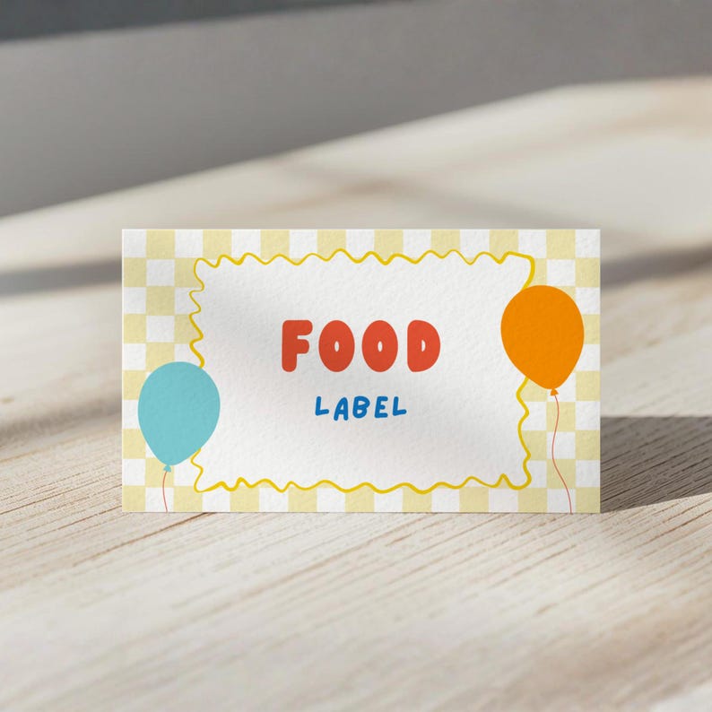 May include: A rectangular food label card featuring a light yellow and white checkered background. The center has a white area with a yellow wavy border, the red text FOOD, the blue text LABEL, a light blue balloon, and an orange balloon.