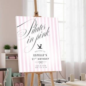 May include: A pink and white striped sign on a wooden easel. The sign reads "Pilates in Pink" in elegant script, with additional text below indicating a birthday celebration. The sign includes a bow graphic and the words "Flex & Flow".