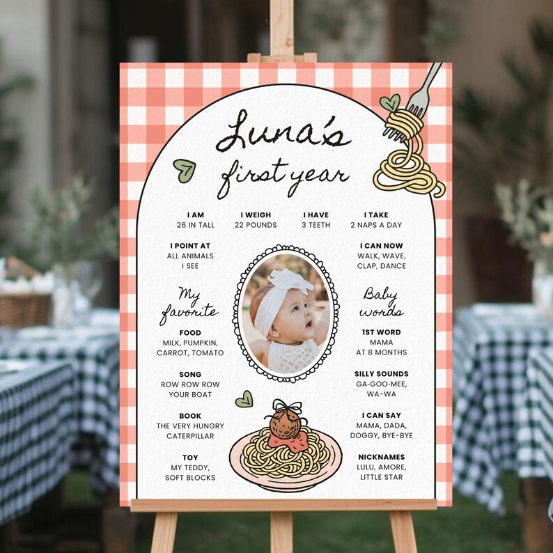 K&ouml;nnte beinhalten: Personalisiertes Schild zum ersten Geburtstag mit einem rosa-wei&szlig; karierten Rand. Das Schild enth&auml;lt ein Foto des Babys und Details &uuml;ber das erste Lebensjahr, wie Gr&ouml;&szlig;e, Gewicht und Lieblingsdinge. Das Schild wird auf einer Holzstaffelei pr&auml;sentiert.