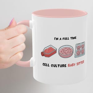 Puede incluir: Taza de cerámica blanca con interior y asa rosas. La taza presenta el texto "I'M A FULL TIME CELL CULTURE BABY SITTER" con ilustraciones de equipos de laboratorio en rojo y rosa.