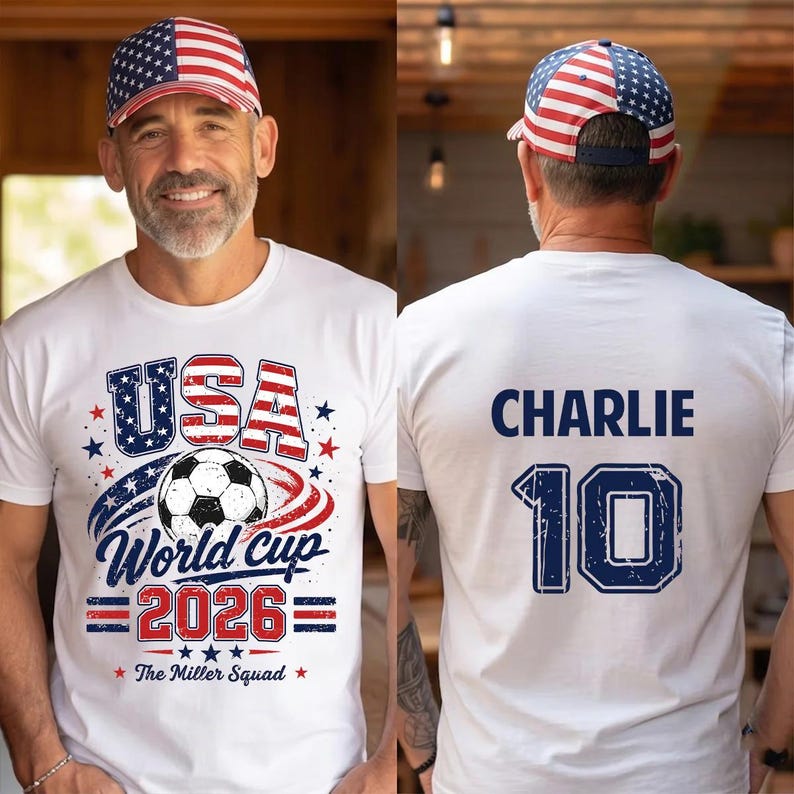 Op de afbeelding: Een wit t-shirt met een afbeelding van een voetbal, de tekst USA World Cup 2026 en The Miller Squad op de voorkant, met de naam CHARLIE en het nummer 10 op de achterkant, gecombineerd met een baseballpet met een Amerikaans vlagpatroon.