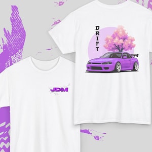 May include: White t-shirts with purple graphics. One shirt features the word "JDM" in purple. The other shirt has a purple car graphic with the word "DRIFT" above it. The shirts are from Dragon Blossom Apparel.