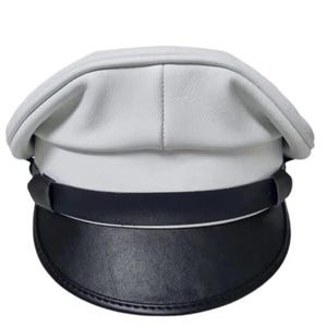 Puede incluir: Un sombrero de cuero blanco y negro con una corona redondeada y un ala plana y curvada. El sombrero presenta una banda negra alrededor de la base y una visera negra. Un sombrero de estilo clásico.