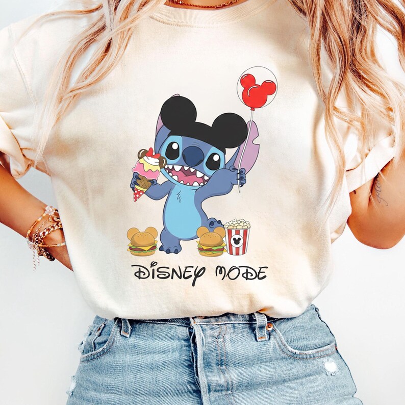 A person wearing a white t-shirt with a cartoon character and text related to Disney.
