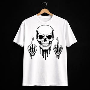 May include: White t-shirt featuring a black and white skull graphic with dripping details and skeleton hands giving the middle finger. The design is centered on the shirt, creating a bold statement.