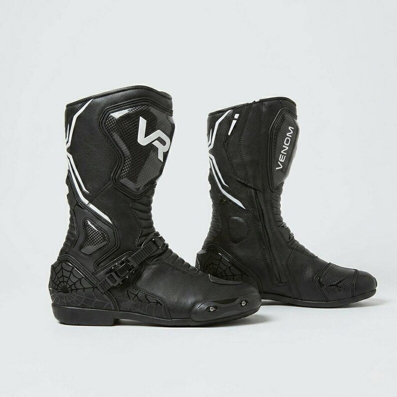 Side view of men's black Venom Racing leather motorcycle boots showing spiderweb embossed toe box carbon shin panel adjustable instep buckle strap and anti-slip rubber outsole