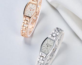May include: Two elegant women's watches. One is rose gold, the other is silver. Both have oval faces with a white dial, slender hands, and a linked bracelet band. The watch face has the word "Lupai" and "Quartz" printed on it.