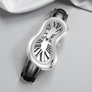 May include: A silver wristwatch with a unique, melting design. The watch face features black Roman numerals on a white background. It has a black leather band. The watch's unusual shape and design make it a statement piece.