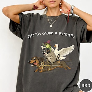 Könnte beinhalten: Eine weiße Keramik-Tasse mit schwarzem Henkel und dem Text "But First, Coffee" in fetter, schwarzer Schrift. Die Tasse steht vor einem verschwommenen Hintergrund, der ihr klares Design hervorhebt.