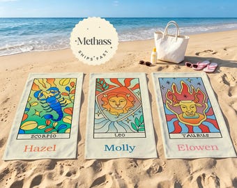 Pode incluir: Três toalhas de praia retangulares com designs coloridos de cartas de tarô do zodíaco para Escorpião, Leão e Touro, personalizadas com os nomes Hazel, Molly e Elowen. Cada toalha exibe uma ilustração vibrante do signo e seu nome.