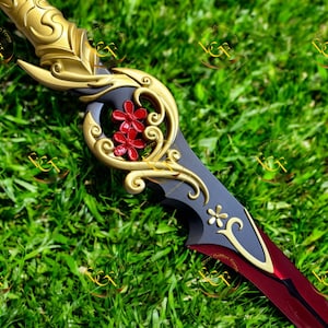 May include: A decorative sword with a gold hilt and accents, featuring a black blade with red and gold details. The sword has a floral design with red flowers and a stylized floral emblem.